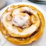 Apple cinnamon roll on a white plate topped with icing