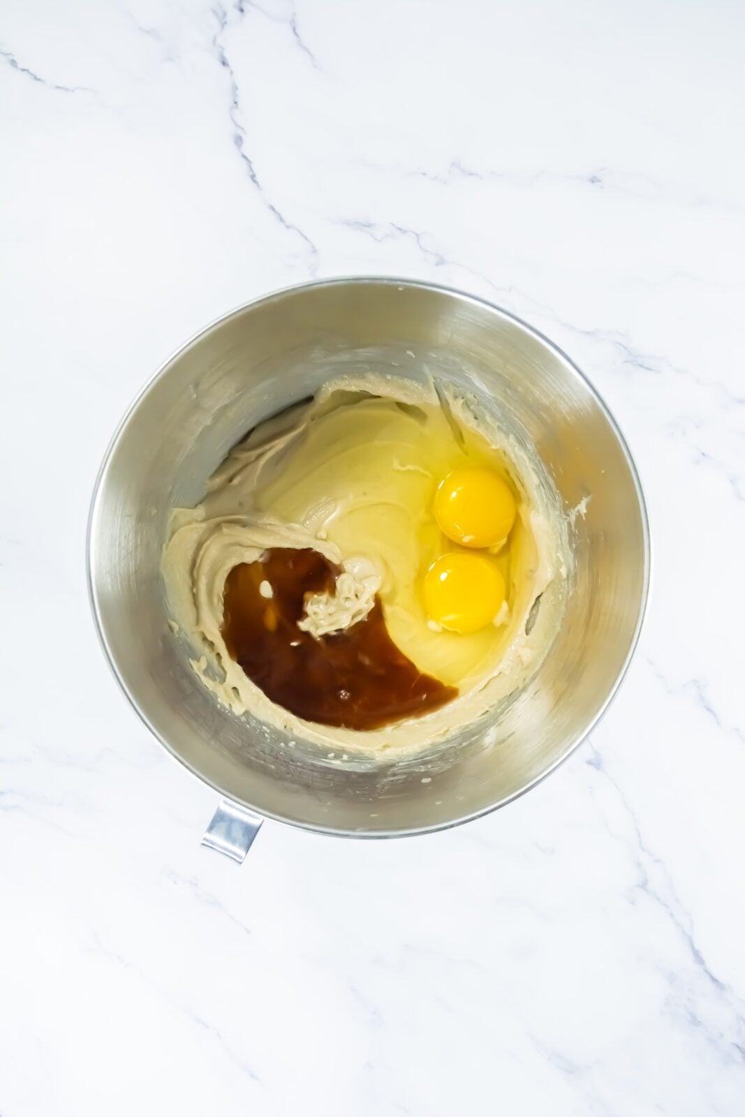 Adding eggs and vanilla to the creamed butter and sugar mixture