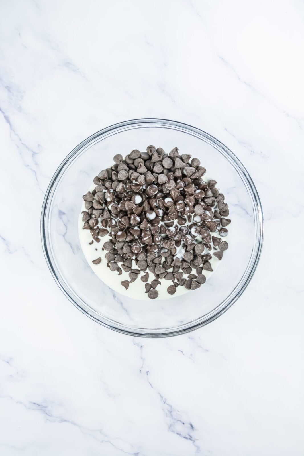 Chocolate chips and heavy cream in a bowl before melting into ganache