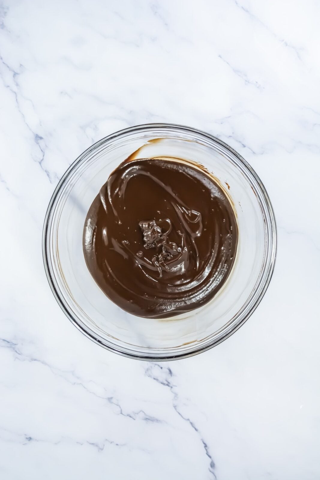 Smooth melted chocolate ganache stirred in a glass bowl