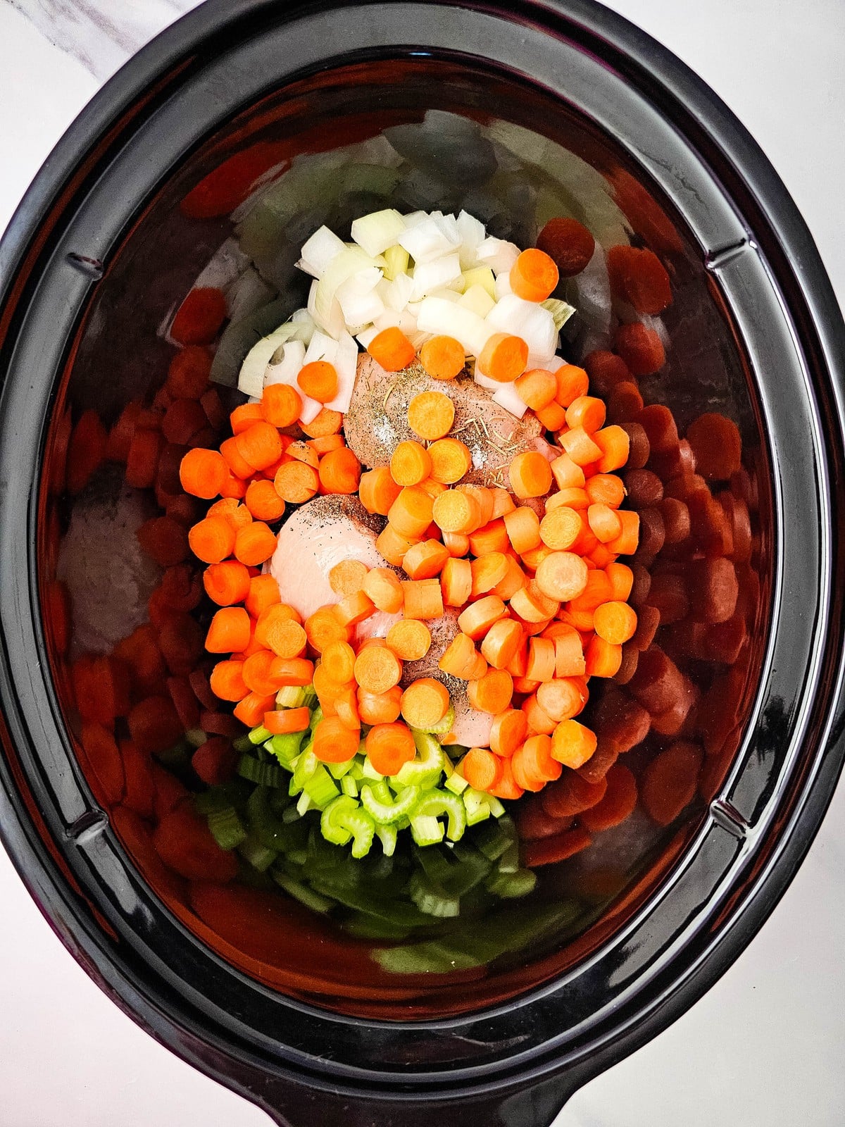 sliced carrots piled on top of the chicken and other vegetables