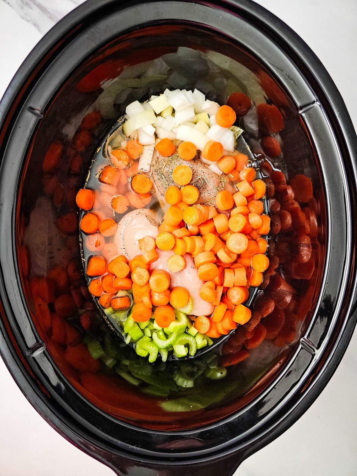 chicken broth poured over the chicken and vegetables