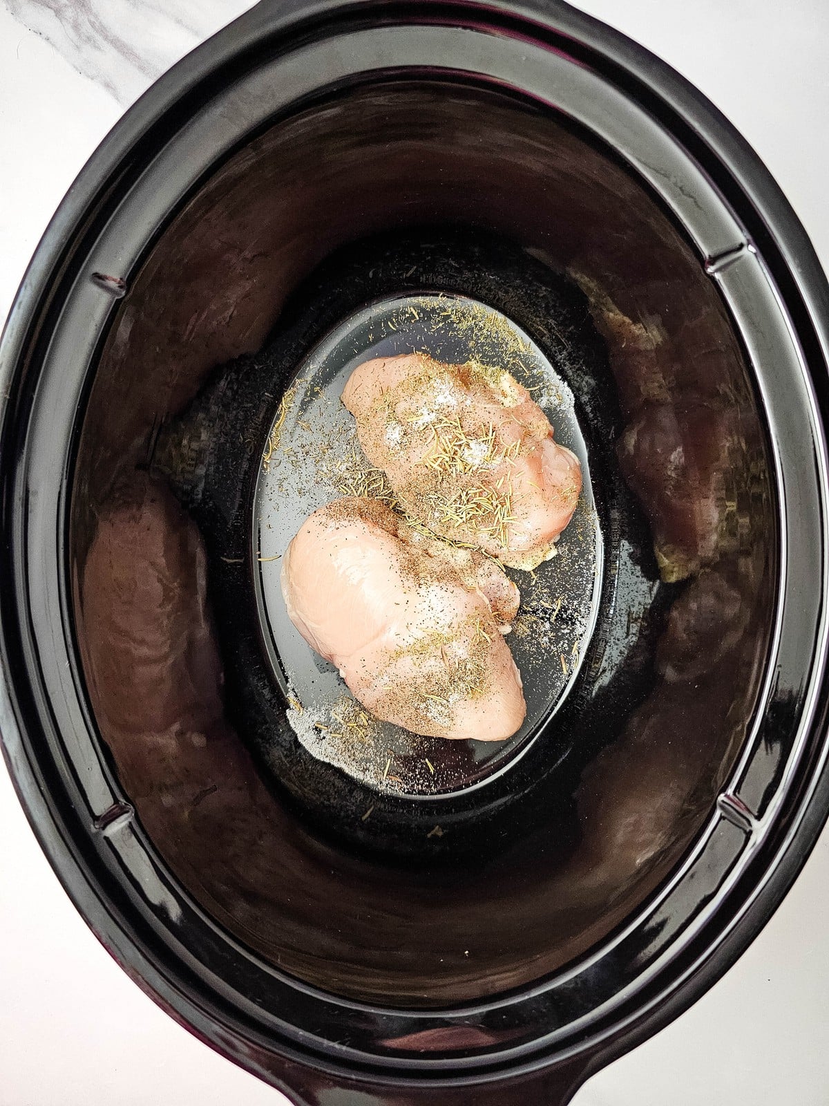 rosemary, thyme, salt and pepper sprinkled over the raw chicken