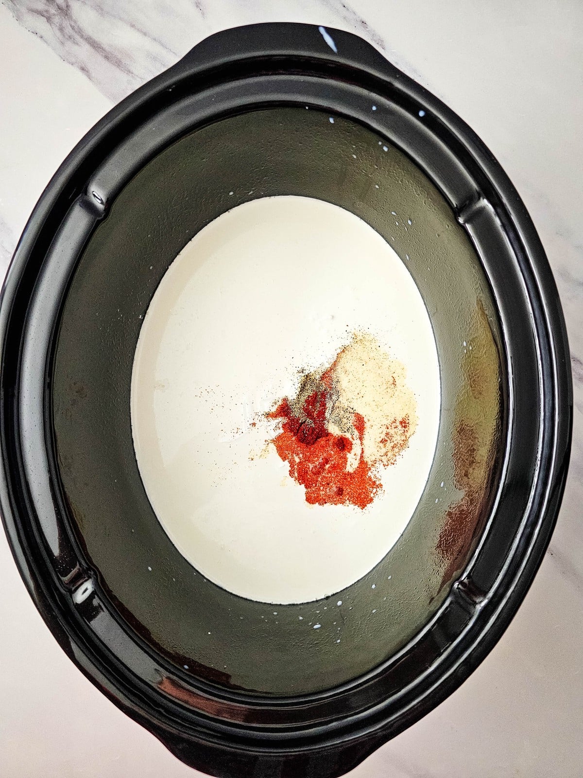Milk, cream and seasonings in the slow cooker before whisking