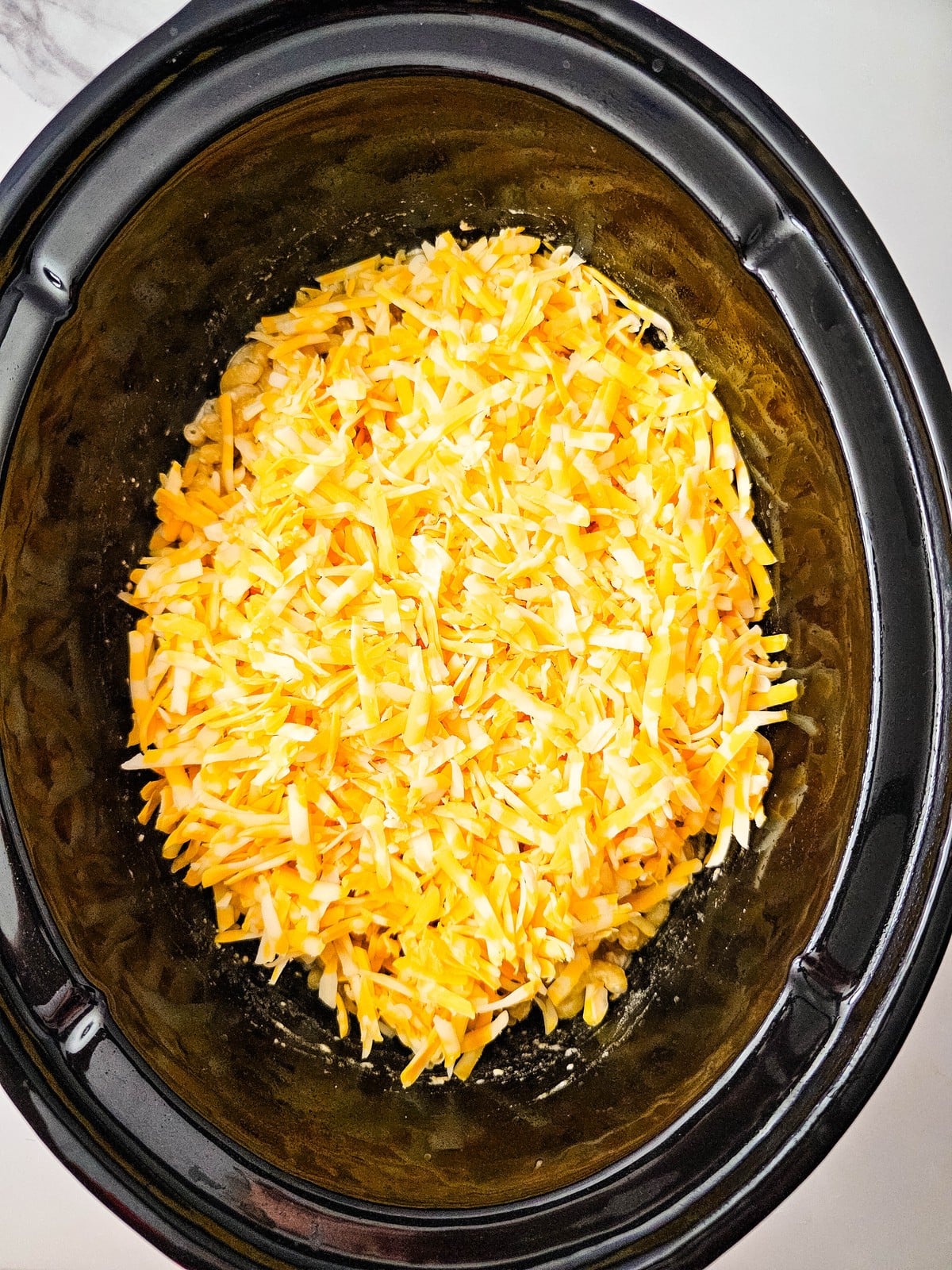 Freshly shredded colby jack piled over the cooked macaroni