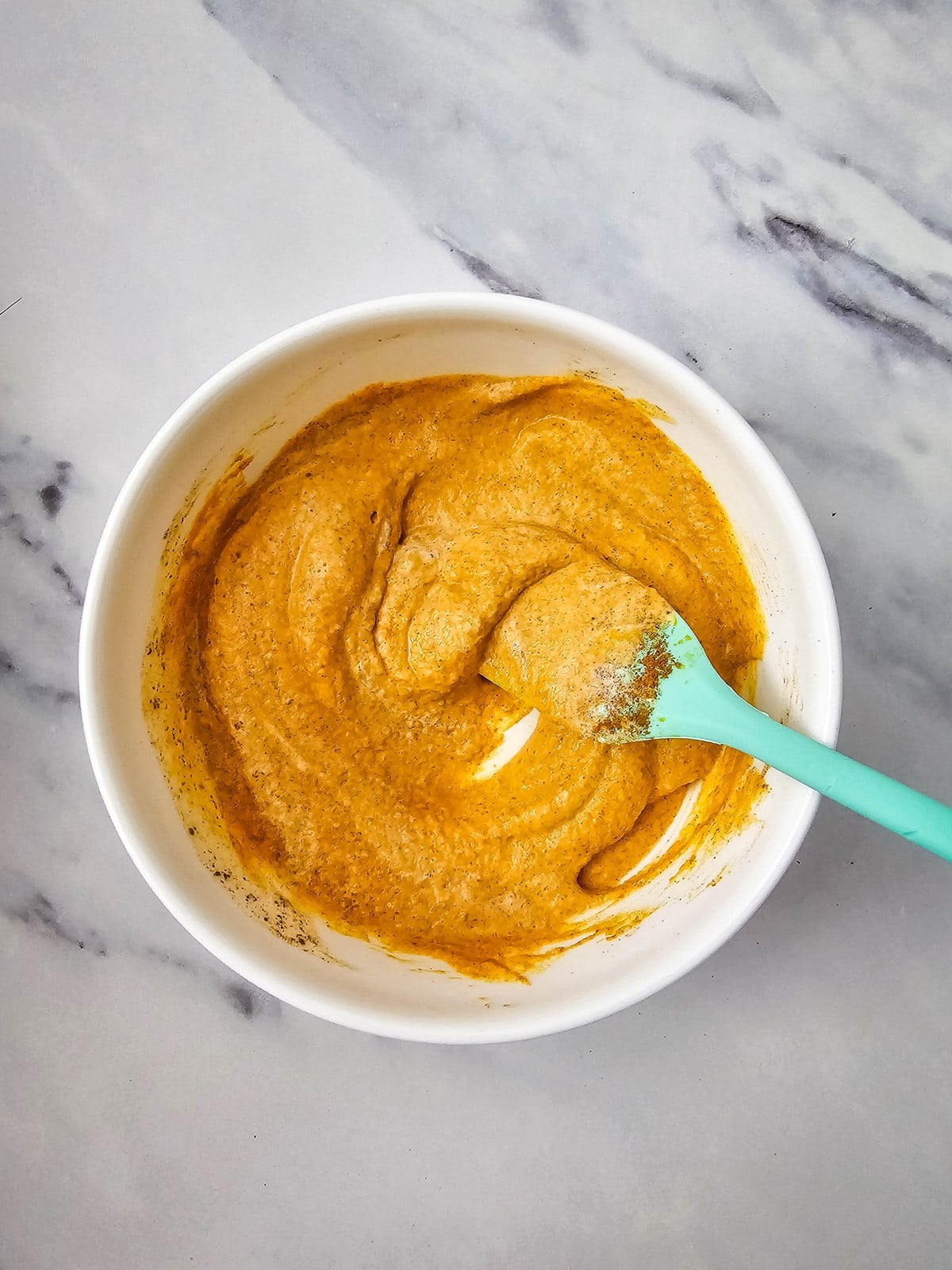 Pumpkin, heavy cream, brown sugar, and pumpkin pie spice stirred together in a white bowl
