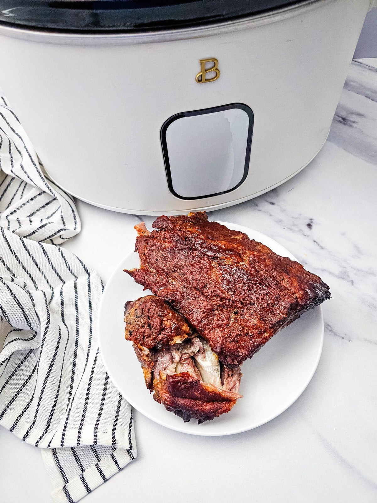 Plate of barbecue crockpot ribs in front of a white slow cooker