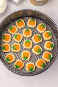 Pumpkin sugar cookie dough pieces pressed into the bottom of a springform pan