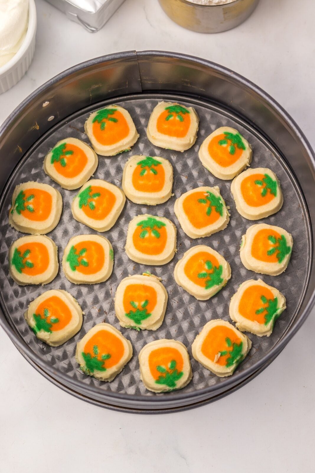 Pumpkin sugar cookie dough pieces pressed into the bottom of a springform pan