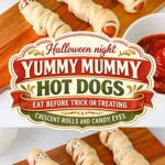 Hot dogs wrapped in crescent roll strips with candy eyes to look like mummies on a wooden board