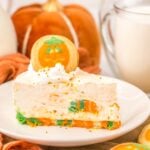 Slice of no bake Halloween cheesecake with milk and pumpkins behind
