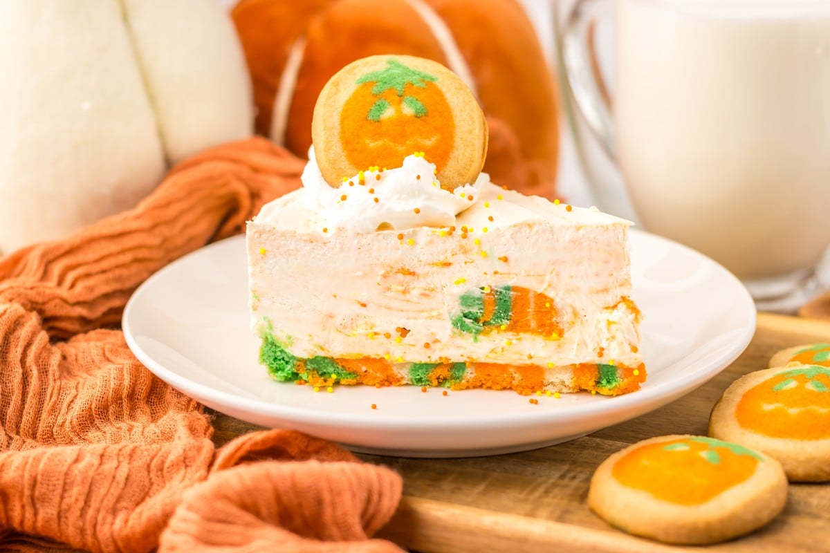 Slice of no bake Halloween cheesecake topped with whipped cream and a pumpkin cookie