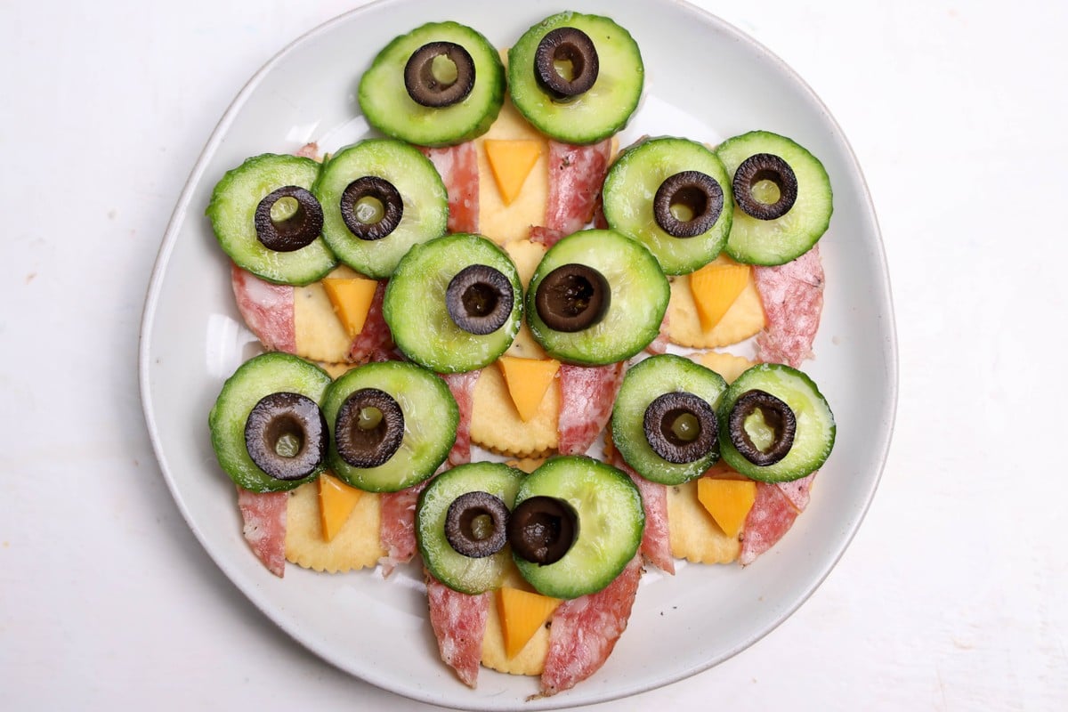 Sliced black olives set on the cucumber rounds to finish the owl cracker eyes