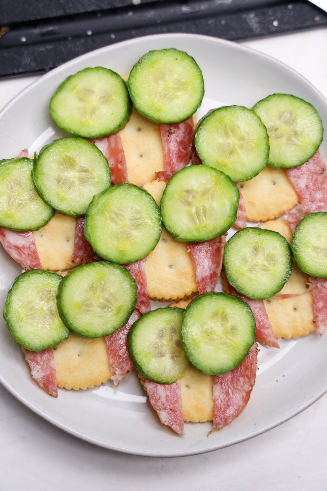Cucumber rounds placed on crackers as the base of the owl eyes