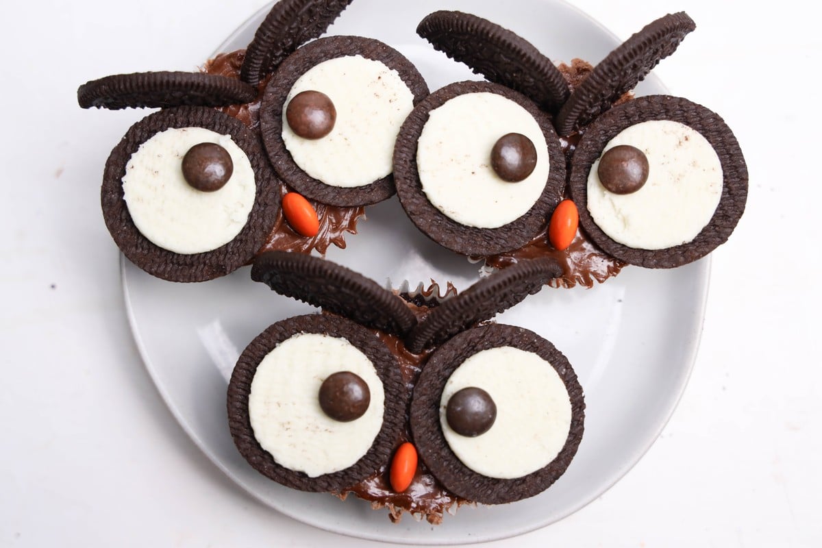 Owl cupcakes with brown Reese&rsquo;s Pieces pupils, orange beaks, and Oreo wafer eyebrows