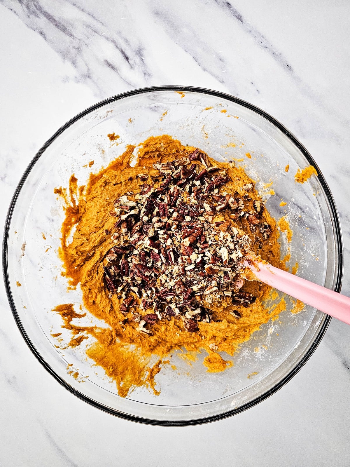 Chopped pecans scattered over pumpkin bread batter before folding in