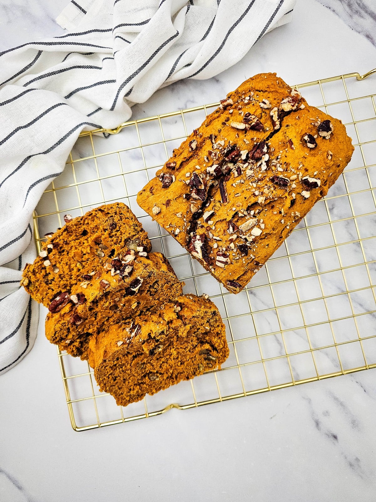 Overhead view of a pumpkin bread loaf and three cut slices on a cooling rack