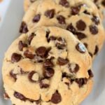 Bakery-style chocolate chip cookies lined up on a white platter.