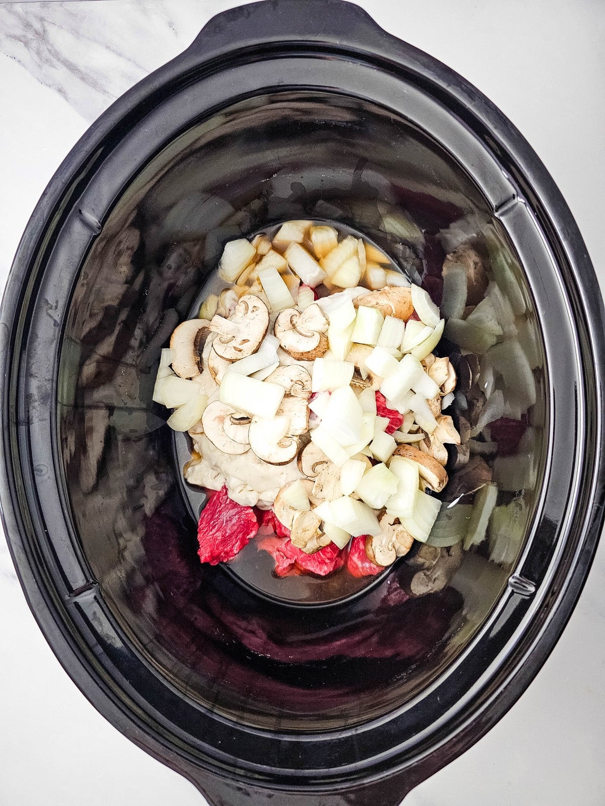 Diced white onion scattered over the mushrooms in the slow cooker