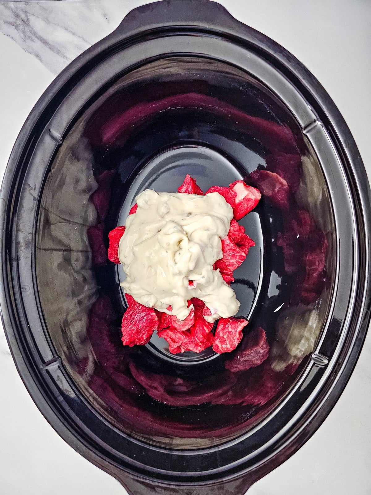 Cream of mushroom soup spooned over raw beef stew meat in the slow cooker