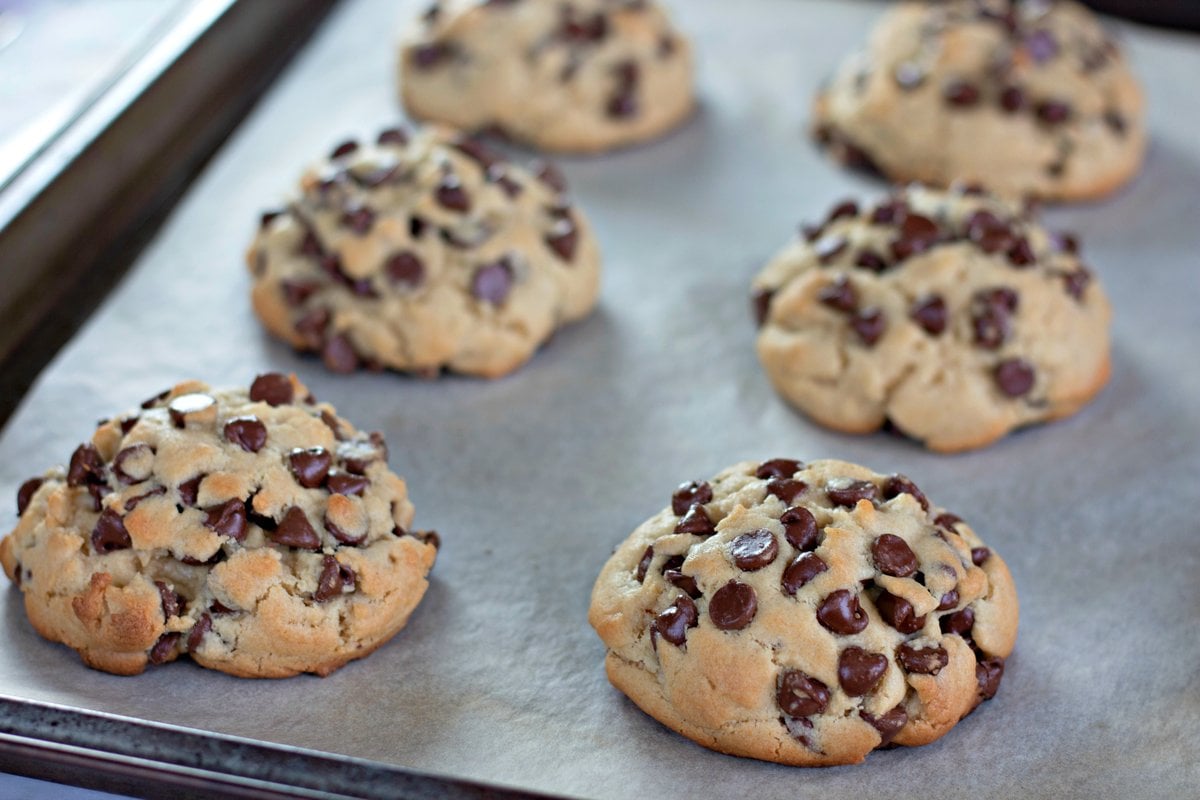 Baked chocolate chip cookies on a parchment-lined baking sheet.