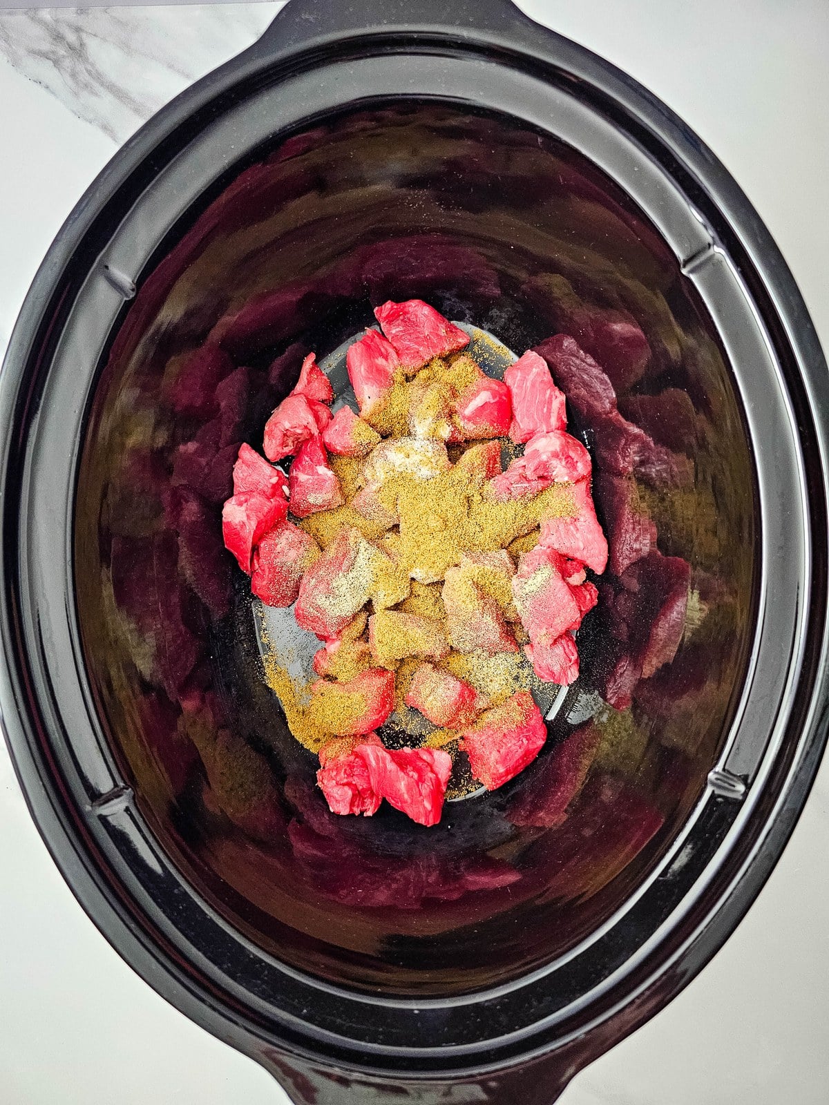 Beef bouillon and garlic added over the seasoned stew meat in the crockpot