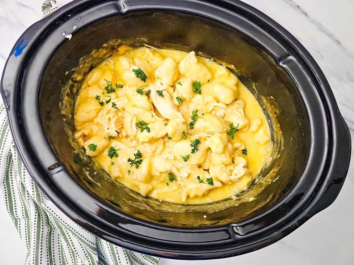 Overhead view of finished crockpot chicken and dumplings in the slow cooker with parsley