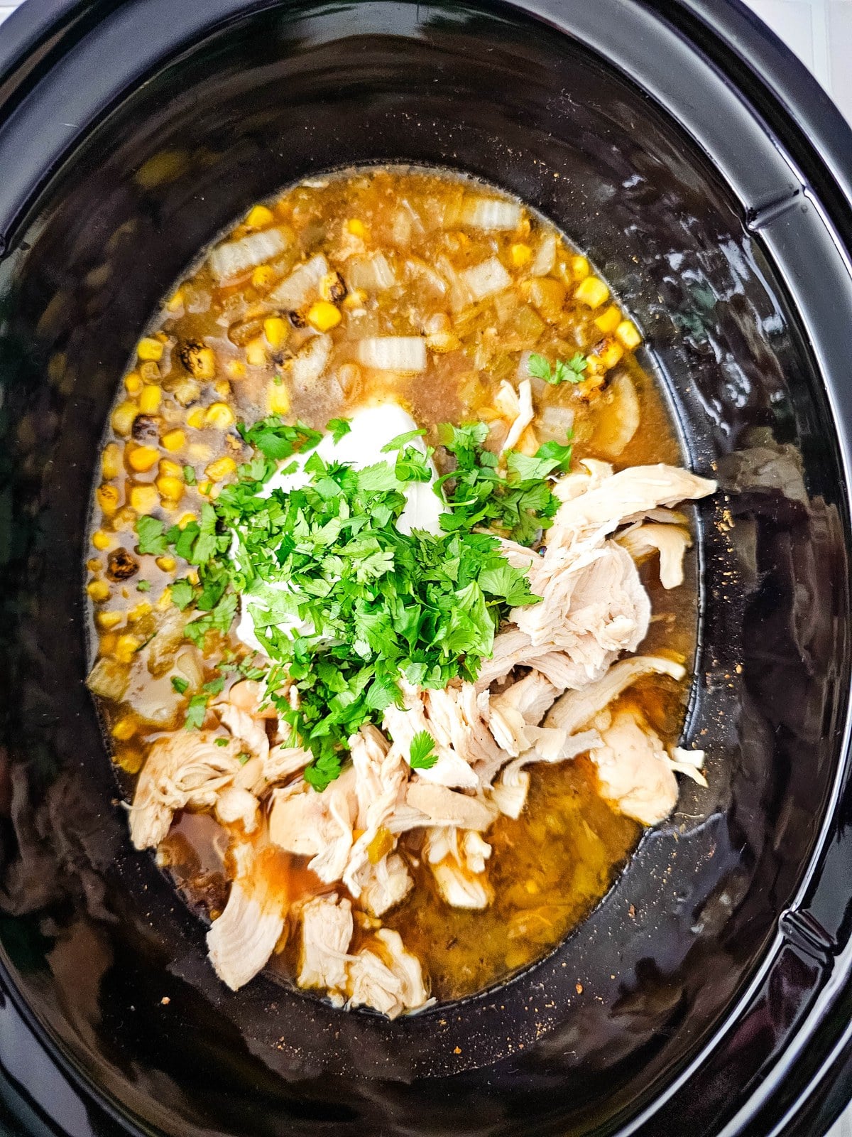 Chopped cilantro added over the cream cheese and shredded chicken in the crockpot