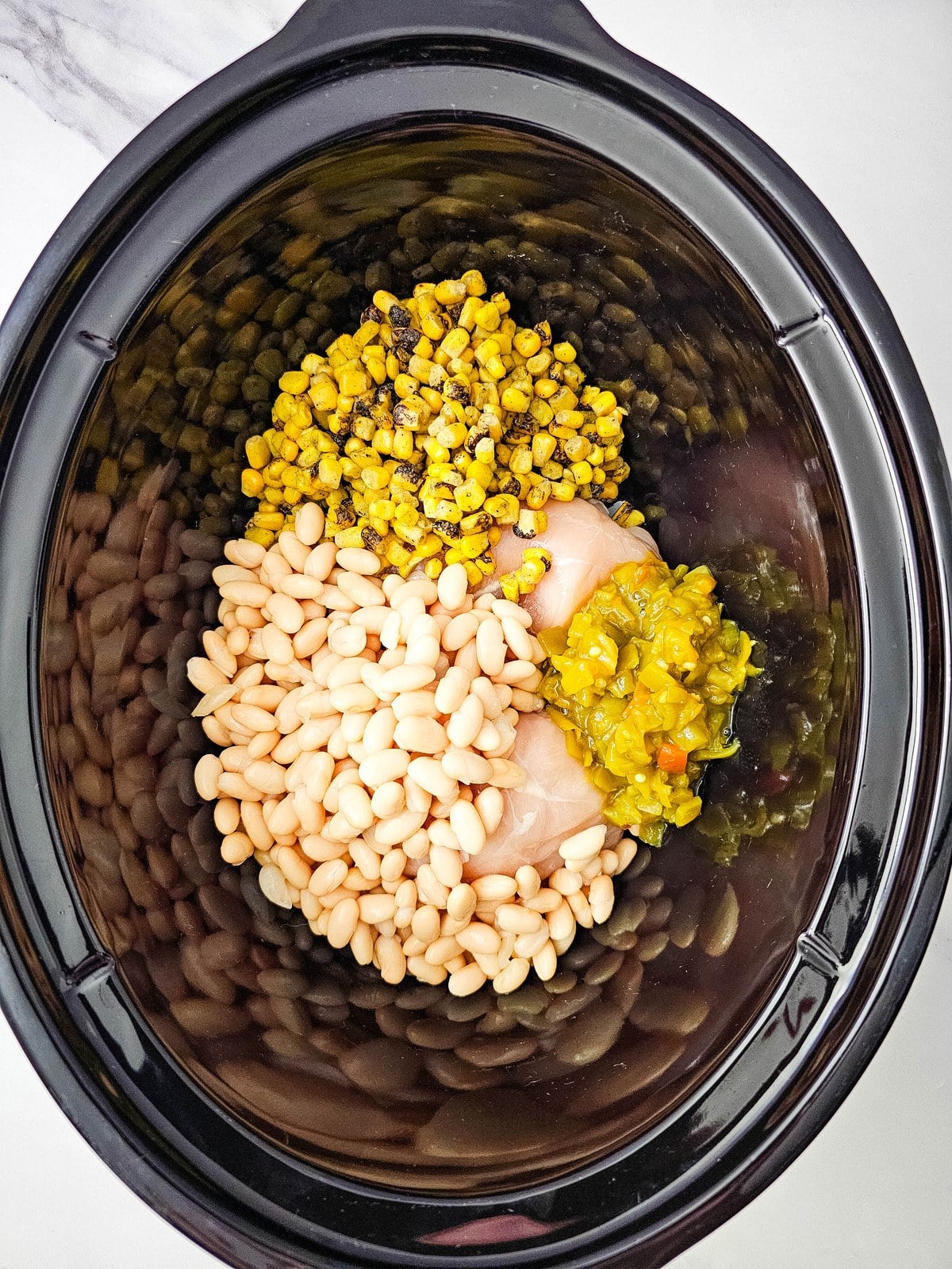 Chopped green chilis added to the crockpot with the beans and corn