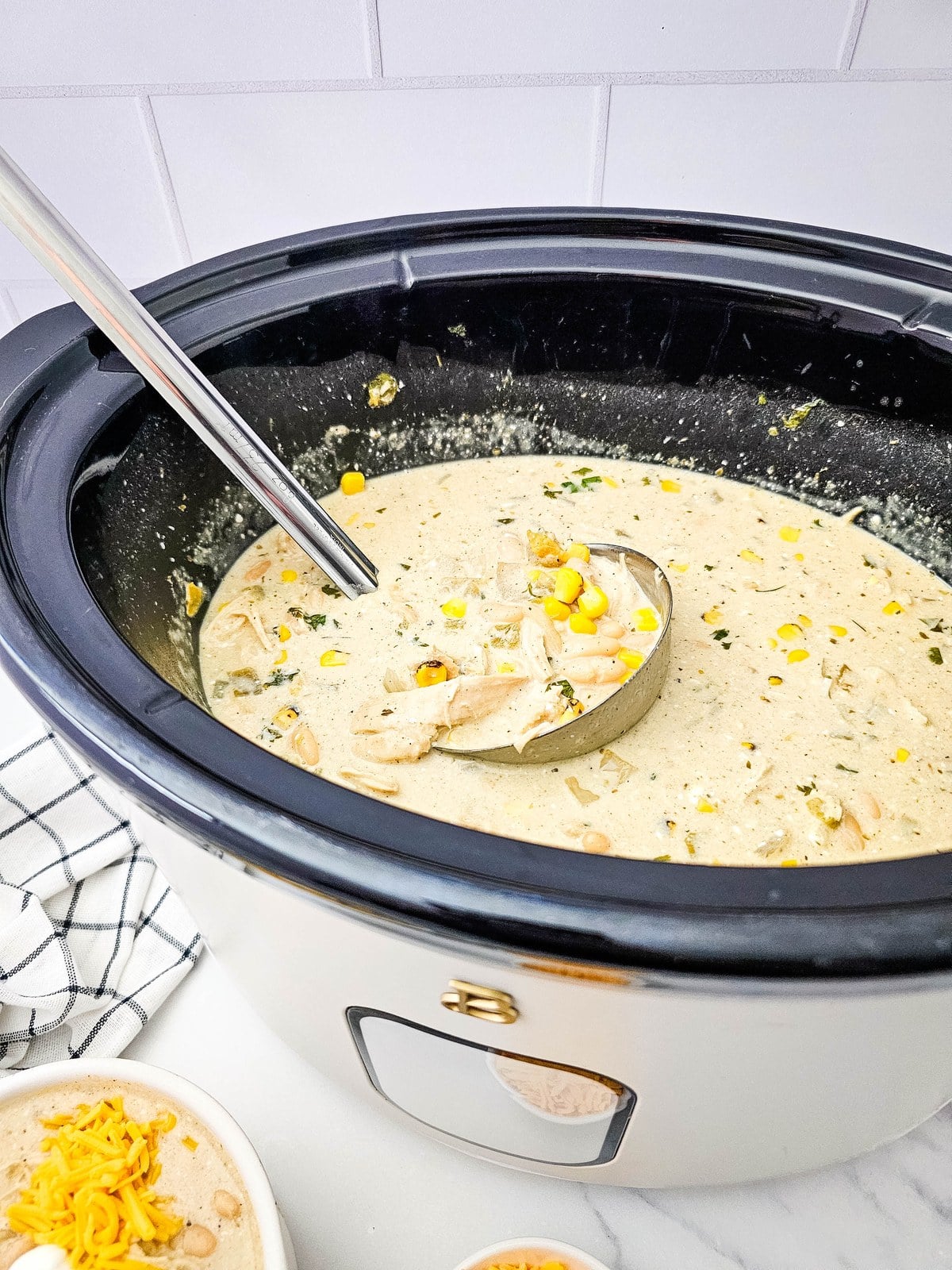 Finished crockpot white chicken chili in the slow cooker with a ladle resting in it