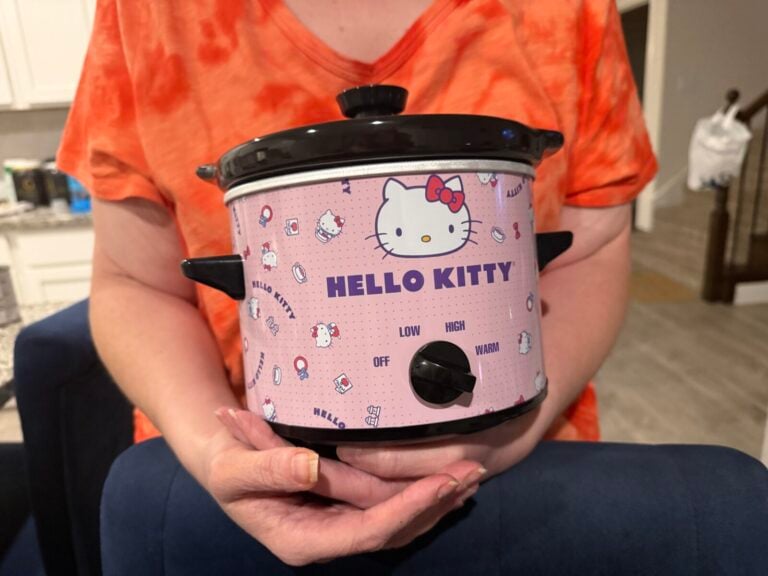 Two hands holding a pink Hello Kitty slow cooker