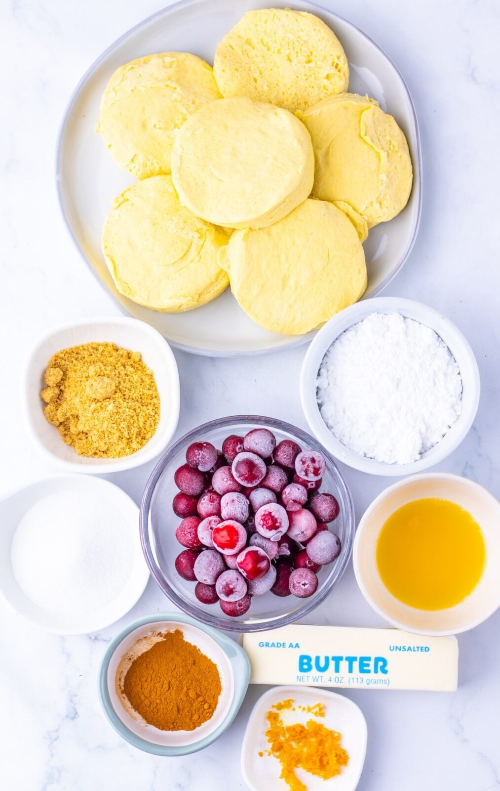 Cranberry Orange Monkey Bread Bites process: gather the canned biscuits, cranberries, granulated sugar, cinnamon, orange zest, butter, brown sugar, powdered sugar,