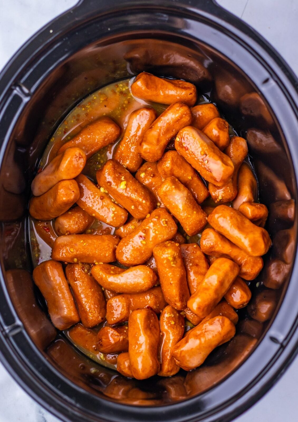 Slow Cooker Maple Dijon Lil Smokies process: add the Lil Smokies to the slow cooker, pour the maple Dijon sauce over them, and stir until every one is coated